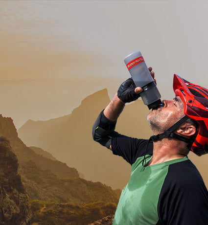 Mountain biker drinking from water filter bottle