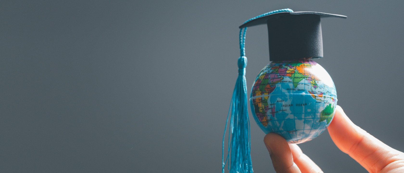 hand holding globe with mortar board 