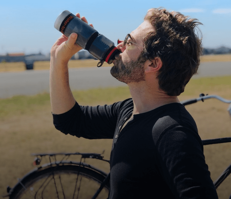 Male cyclist drinking from water filter bottle