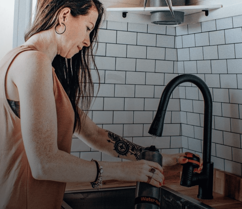 Woman at home filling water filter bottle