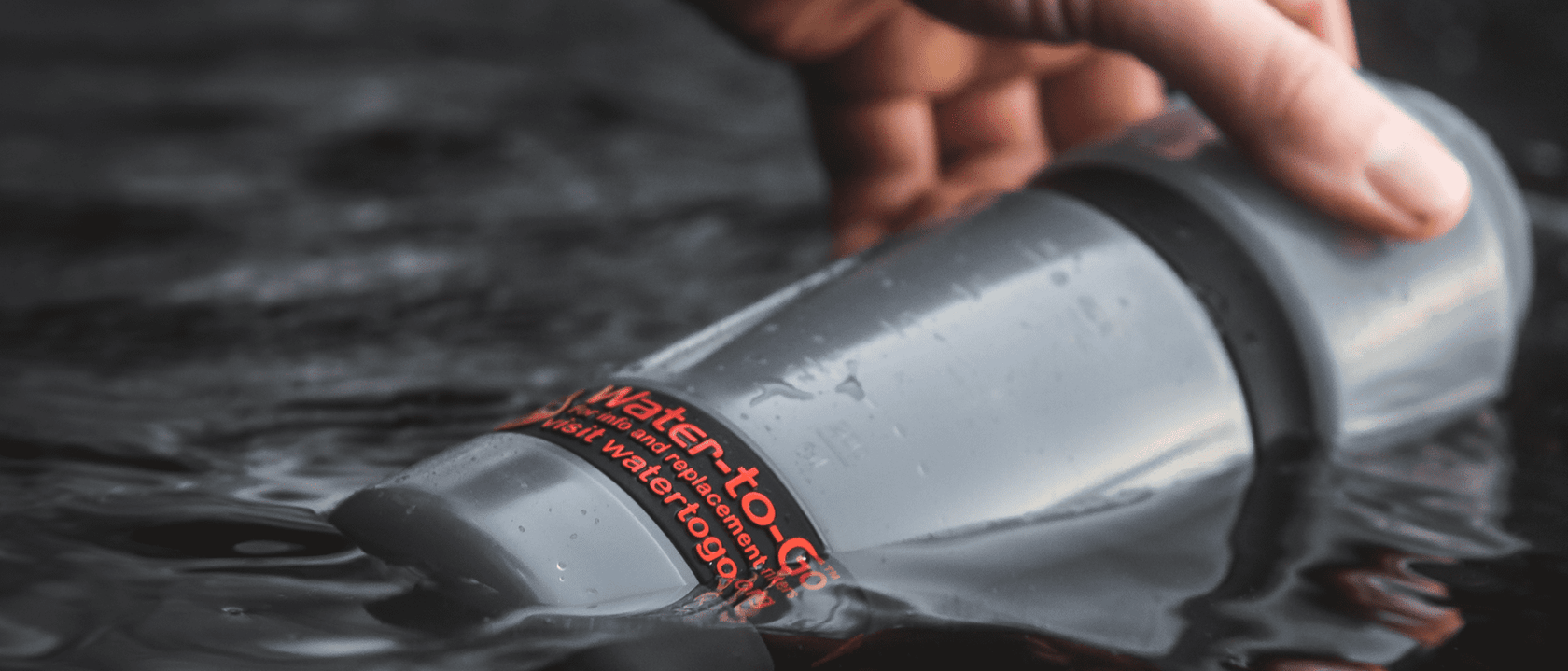 Active water filter bottle being filled at lake