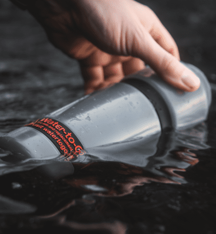 bike water bottle with filter being filled at a lake